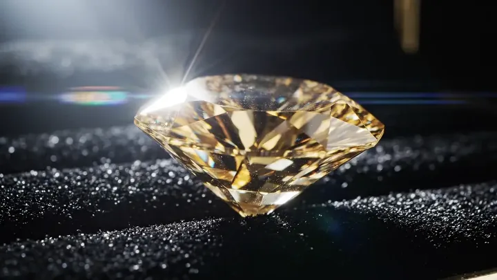 A gold diamond resting on black glittering sand